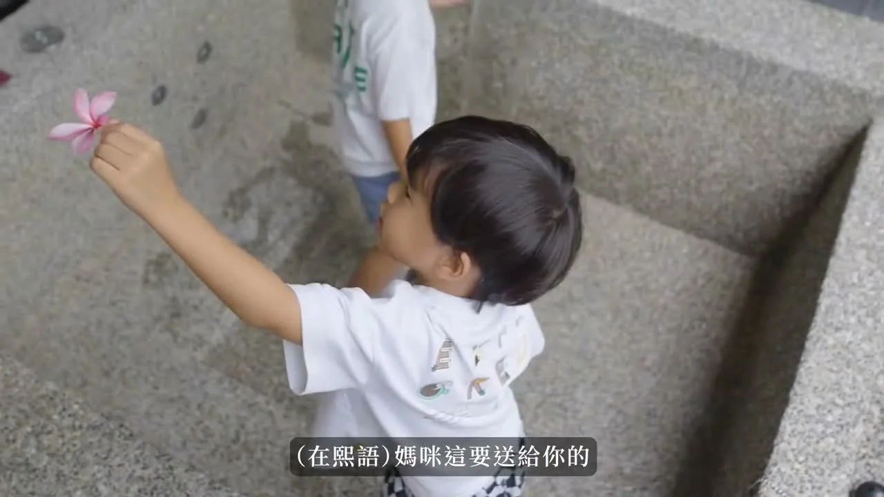 孩子在凱撒房外拿著一朵粉紅色花送給媽媽