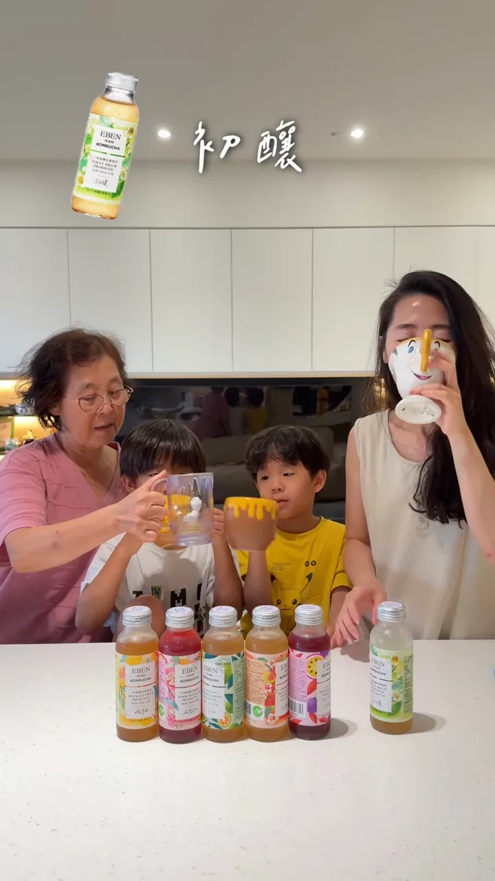 YouTube 影片截圖：家人坐在餐桌前，面前排著多瓶 EBEN 康普茶