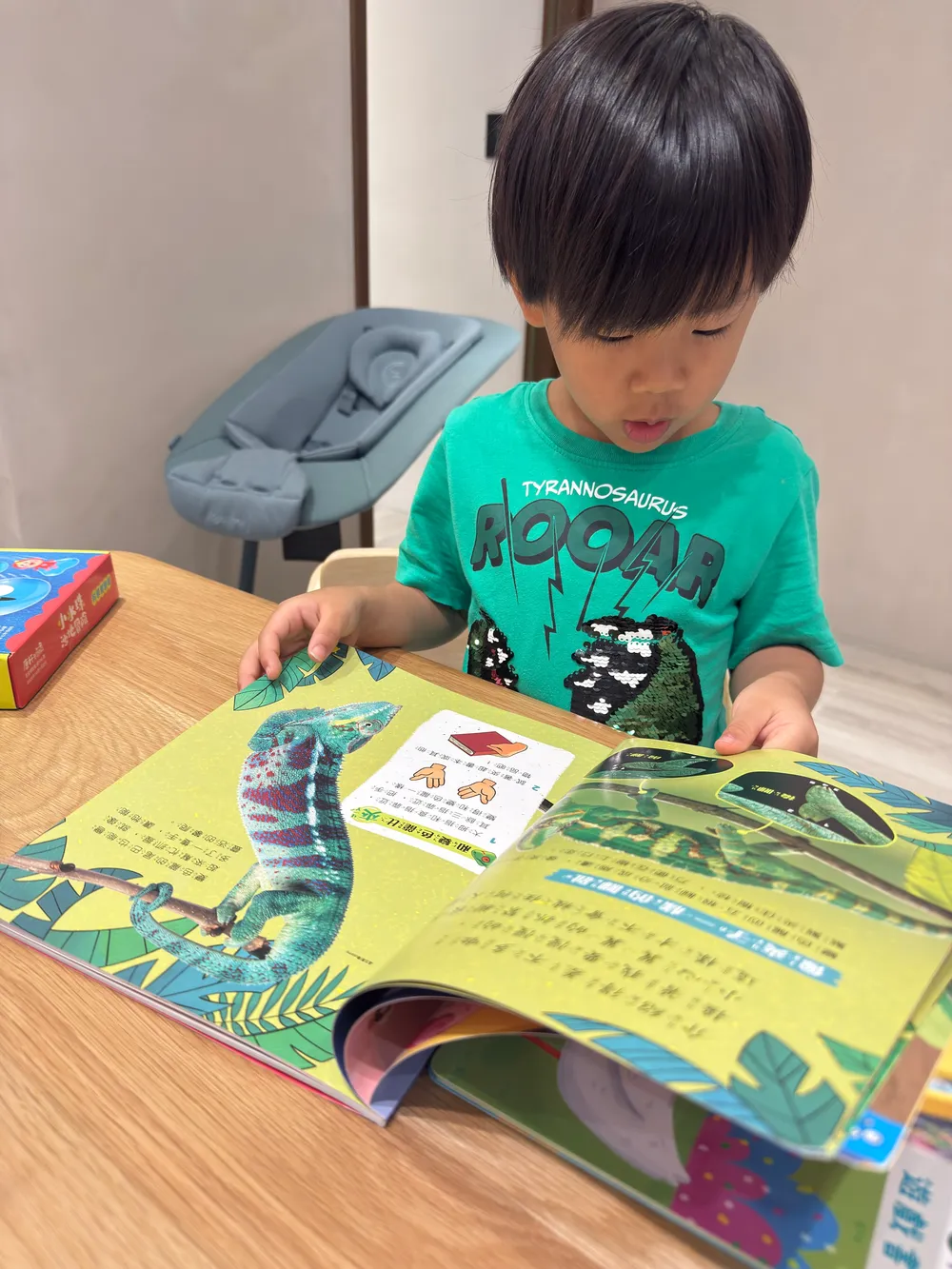 孩子在桌前翻看有變色龍圖片與翻頁機關的康軒雜誌