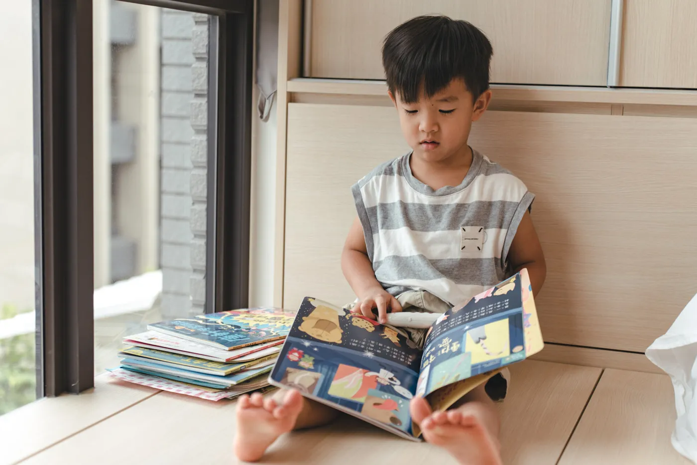 孩子坐在窗邊,用點讀筆搭配攤開的雜誌