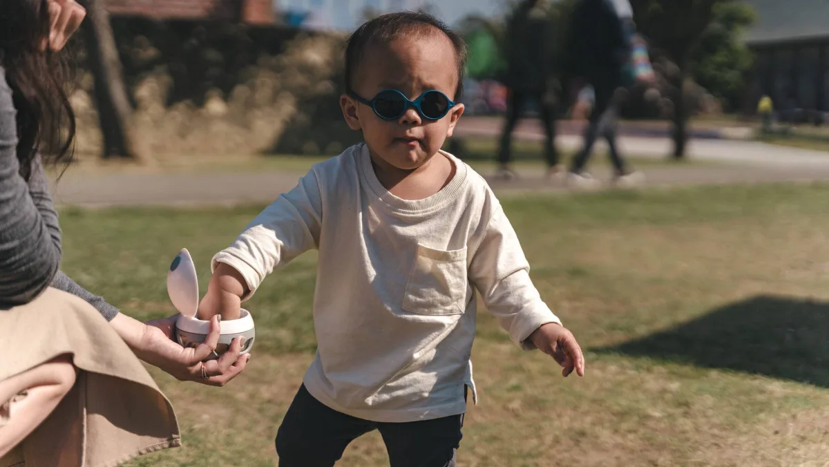 孩子在戶外伸手從 ELLE 零食球裡拿取點心