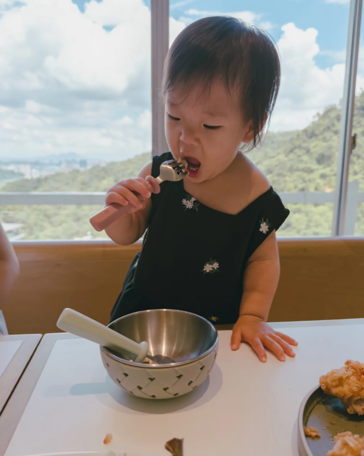 舟夏站在餐桌前，握著 Meroware 叉子自己吃飯，桌上放著餐碗