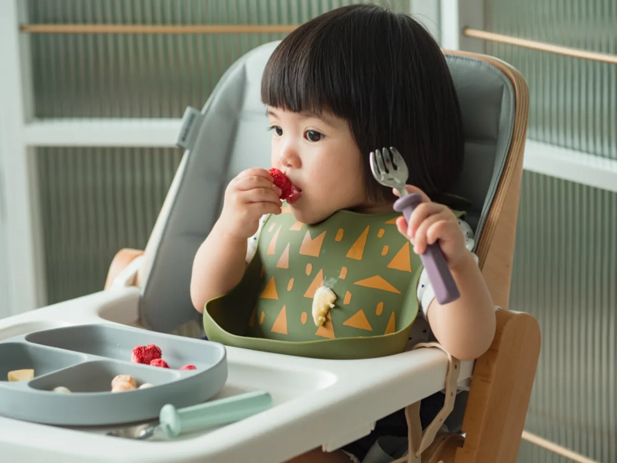 孩子穿著 GINA 小捕手立體圍兜吃飯，前方有立體承接袋
