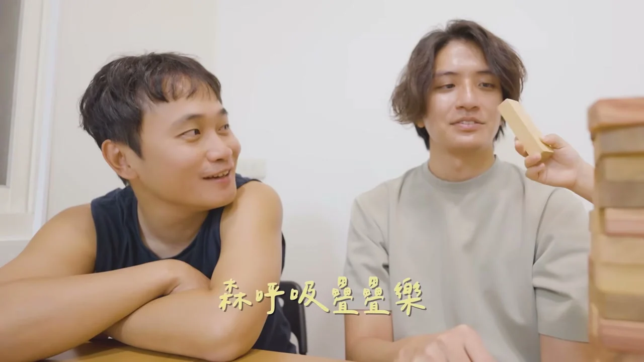 桌前拿著木塊交談，旁邊疊著一座木塊塔