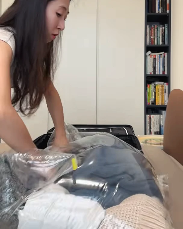 雙手壓在裝滿衣物的透明收麻吉壓縮袋上,實際進行排氣收納