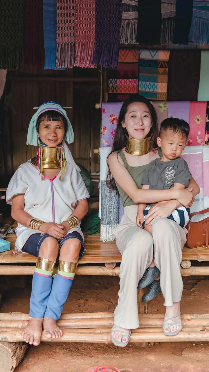 Queenie 抱著孩子，在織品攤位前和當地居民合照