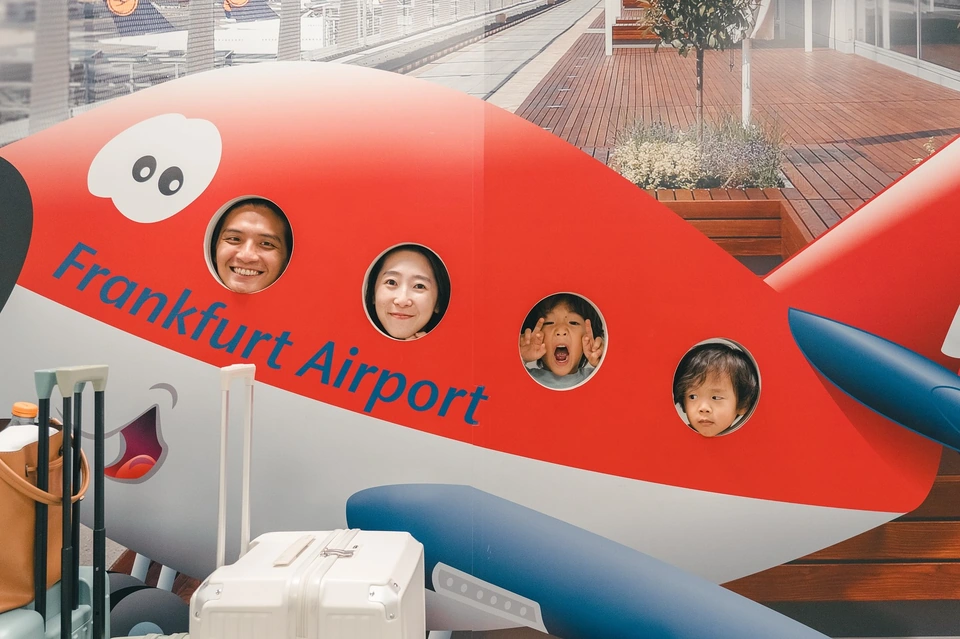 一家人把頭伸進法蘭克福機場的紅色飛機造型看板
