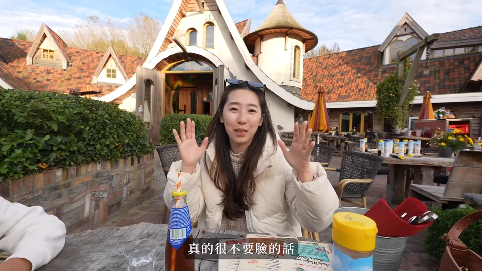媽媽坐在桌旁,後方是童話造型建築