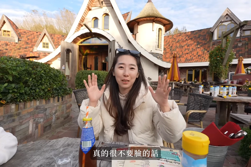 媽媽坐在桌旁,後方是童話造型建築