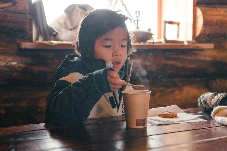 孩子在小屋裡拿著杯子和湯匙