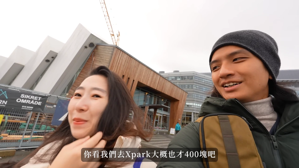 爸爸媽媽在 Polaria 的傾斜造型建築前,前方有施工圍欄