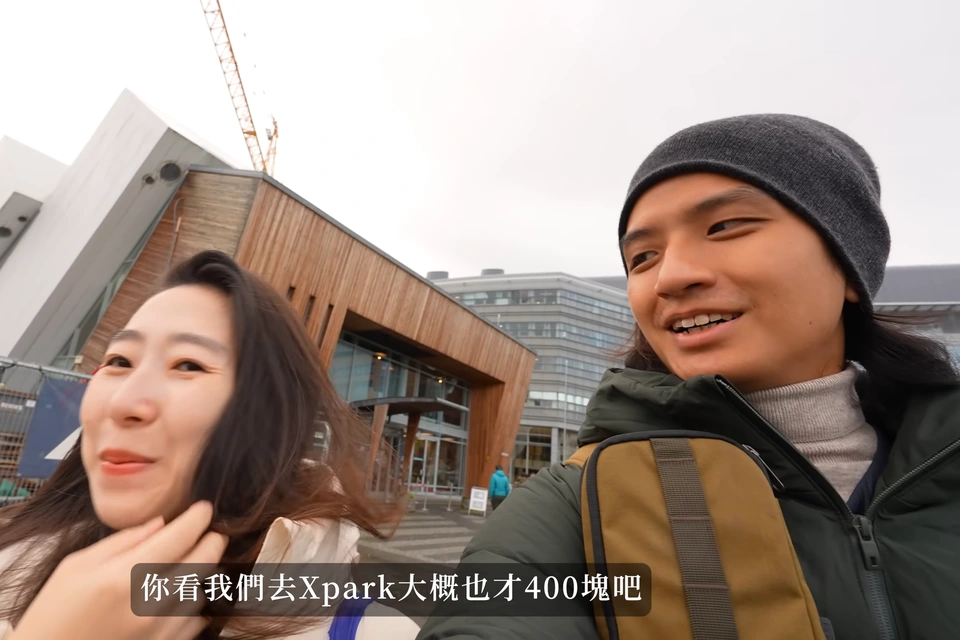 爸爸媽媽在 Polaria 的傾斜造型建築前，前方有施工圍欄
