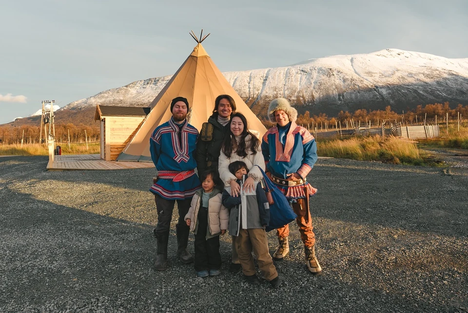 一家人和兩位 Sámi 接待者在黃色帳篷前合照