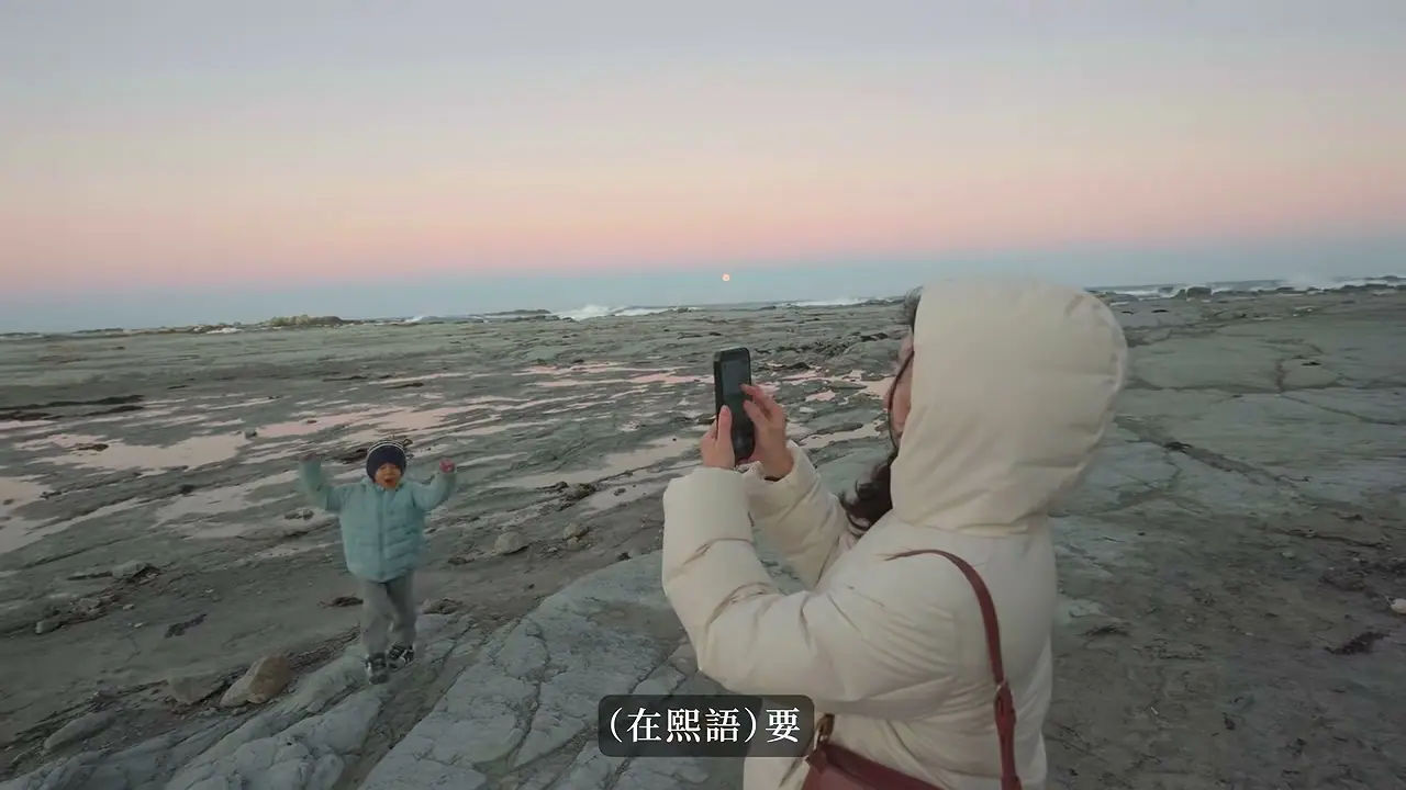 傍晚岩岸上孩子面向家人拍照