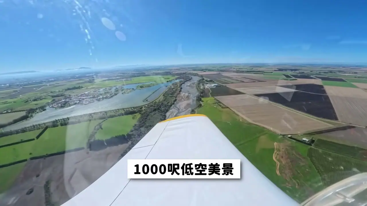 從飛行中的小飛機機翼旁俯看農田、河道與城鎮