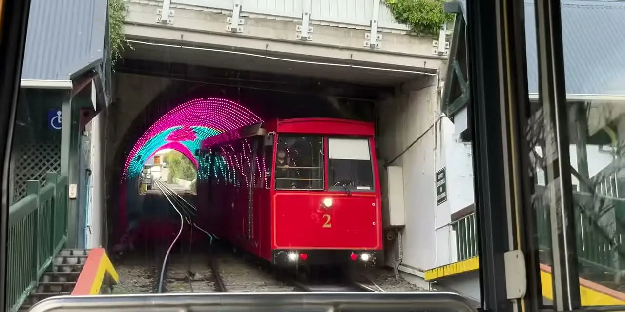 威靈頓紅色纜車從彩色燈光隧道駛進車站