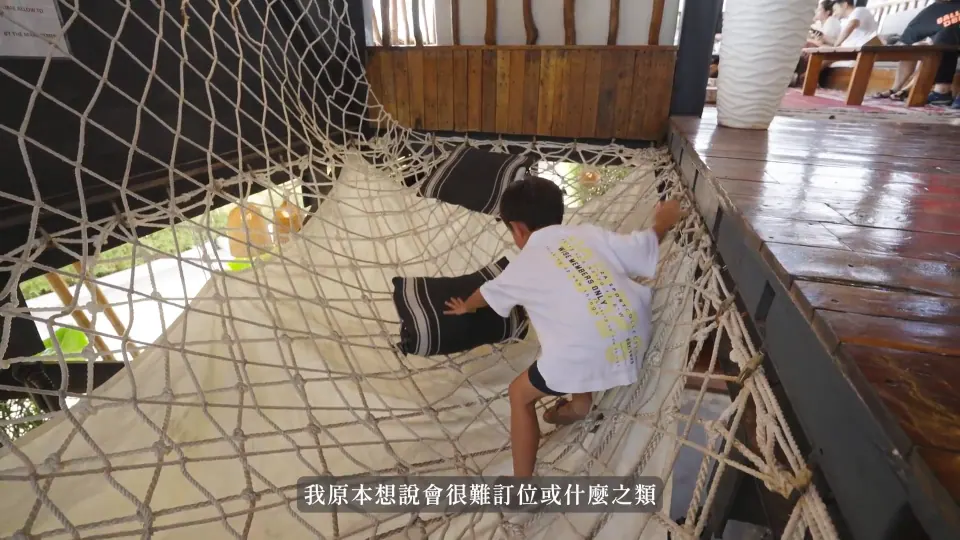 孩子在 MIST 網繩空間裡,旁邊有木地板、靠枕與用餐座位。