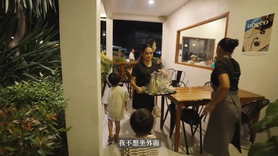 家人走入 Ubeco 用餐空間,牆面海報可見店名。