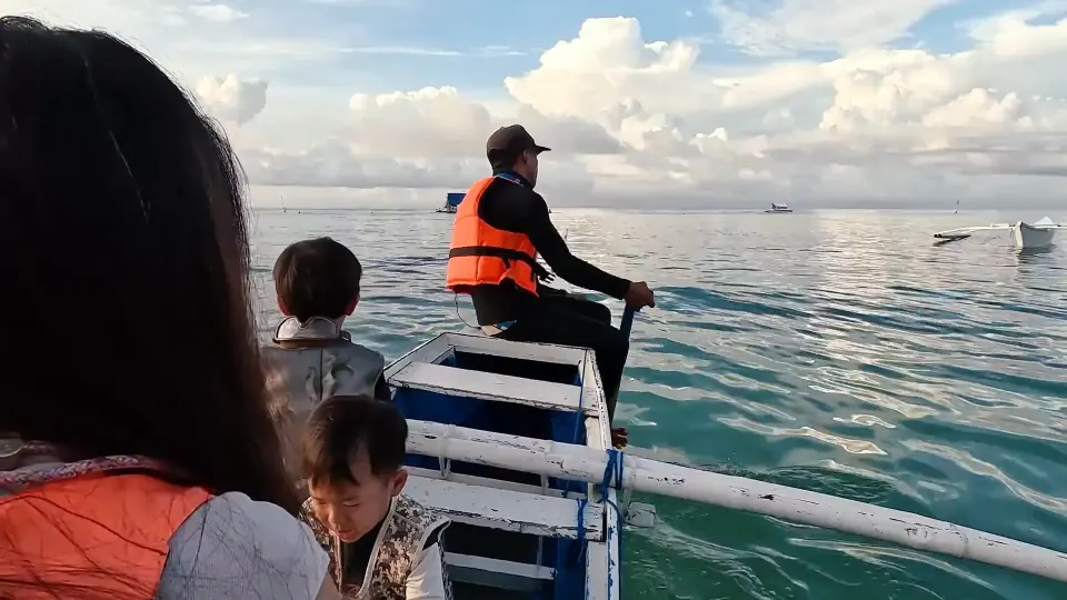 家人與船員坐在小船上,周圍是海面與其他船隻。