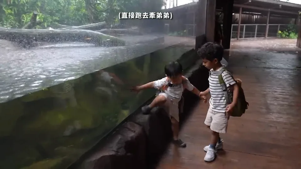 兩個哥哥站在河川生態園水槽前,其中一人伸手指向水面。