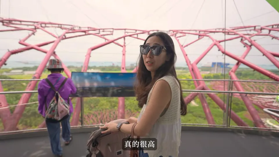 秀秀站在擎天樹觀景處,阿婆在後方欄杆旁,身後可見粉紅色樹冠結構。